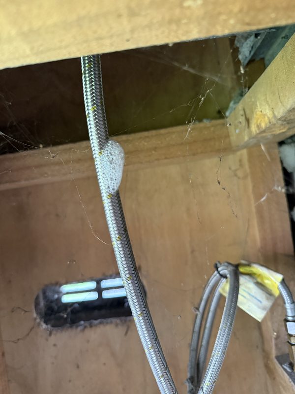 Before: leak-detection fluid bubbling on a braided flexible gas hose under a Hornby house