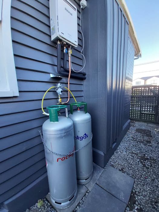 Gas hot water conversion &mdash; Rinnai continuous flow unit and twin LPG bottles, certified on completion