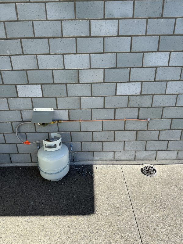 LPG bottle, regulator and copper gas supply line installed on a brick wall in Rolleston