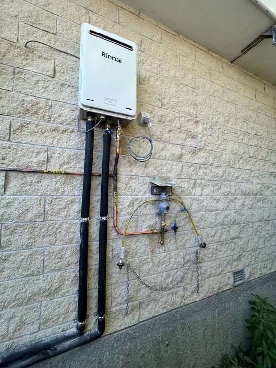 Rinnai Infinity gas hot water unit installed on a brick exterior wall with LPG regulator, Christchurch